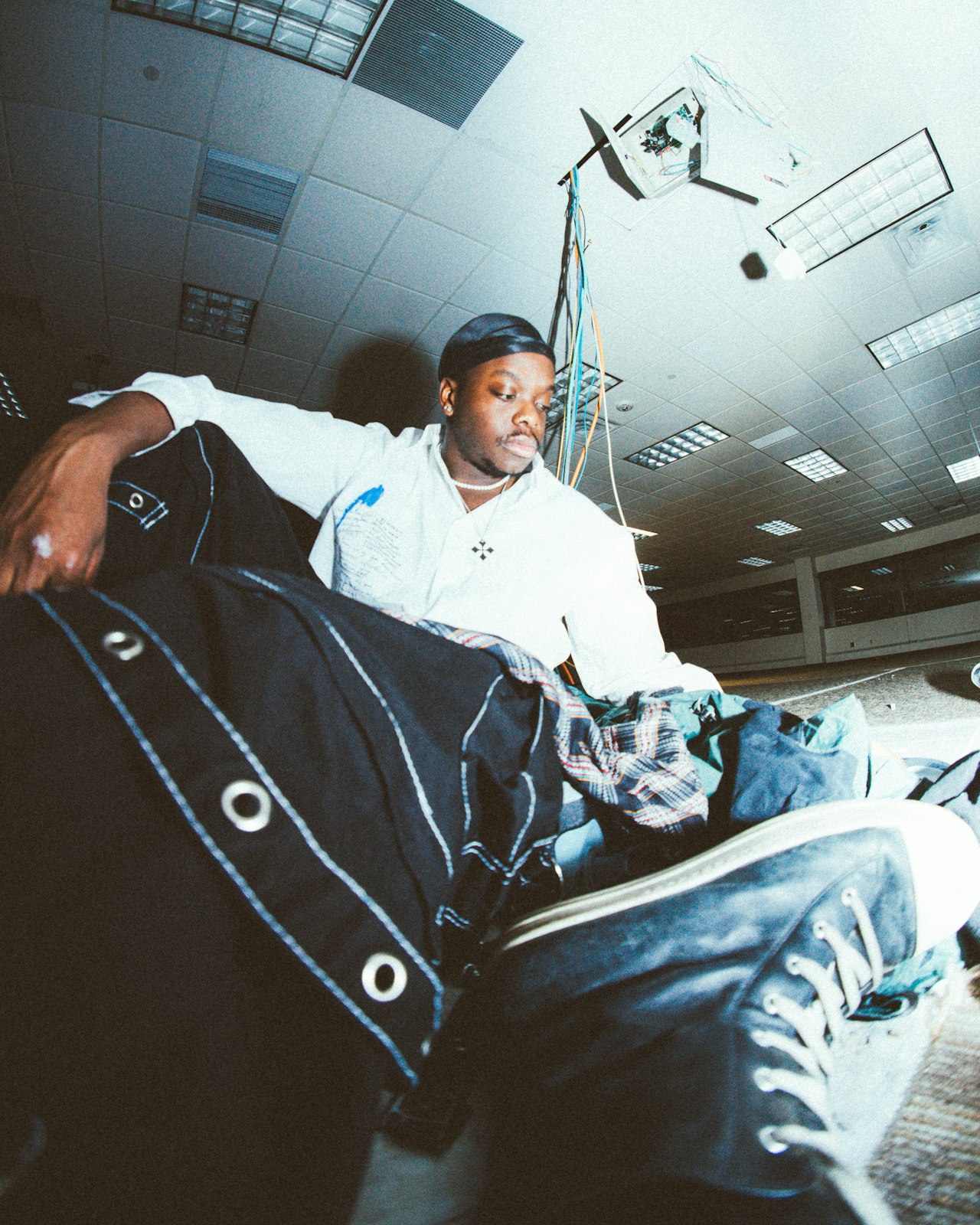 A traveller resting on a suitcase while waiting in an airport hall